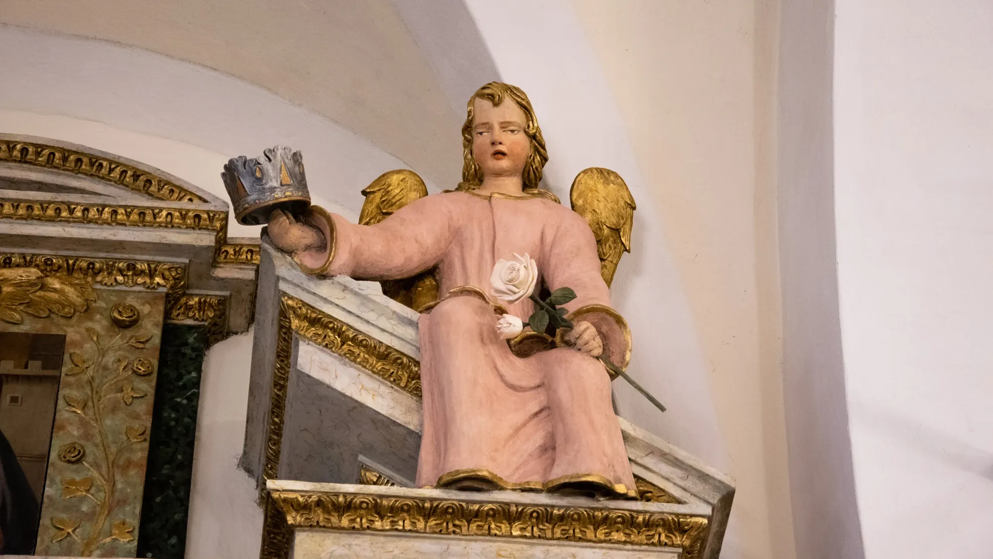 Statua di un angelo in una chiesa che regge la corona e la rosa realizzate per il restauro di Ripabianca