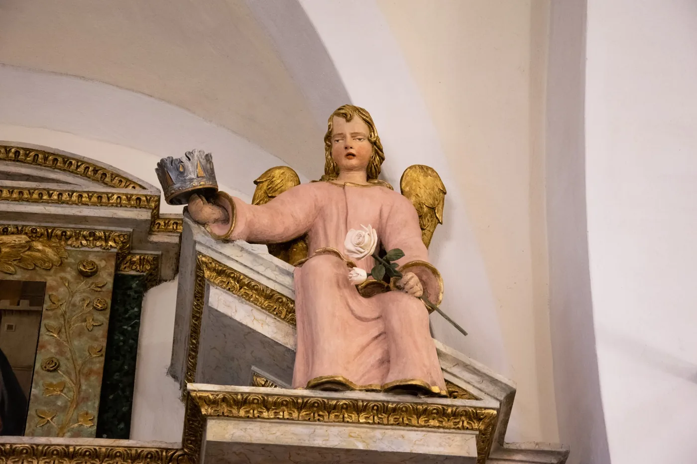 Statua di un angelo in chiesa con la corona e la rosa realizzate per il restauro